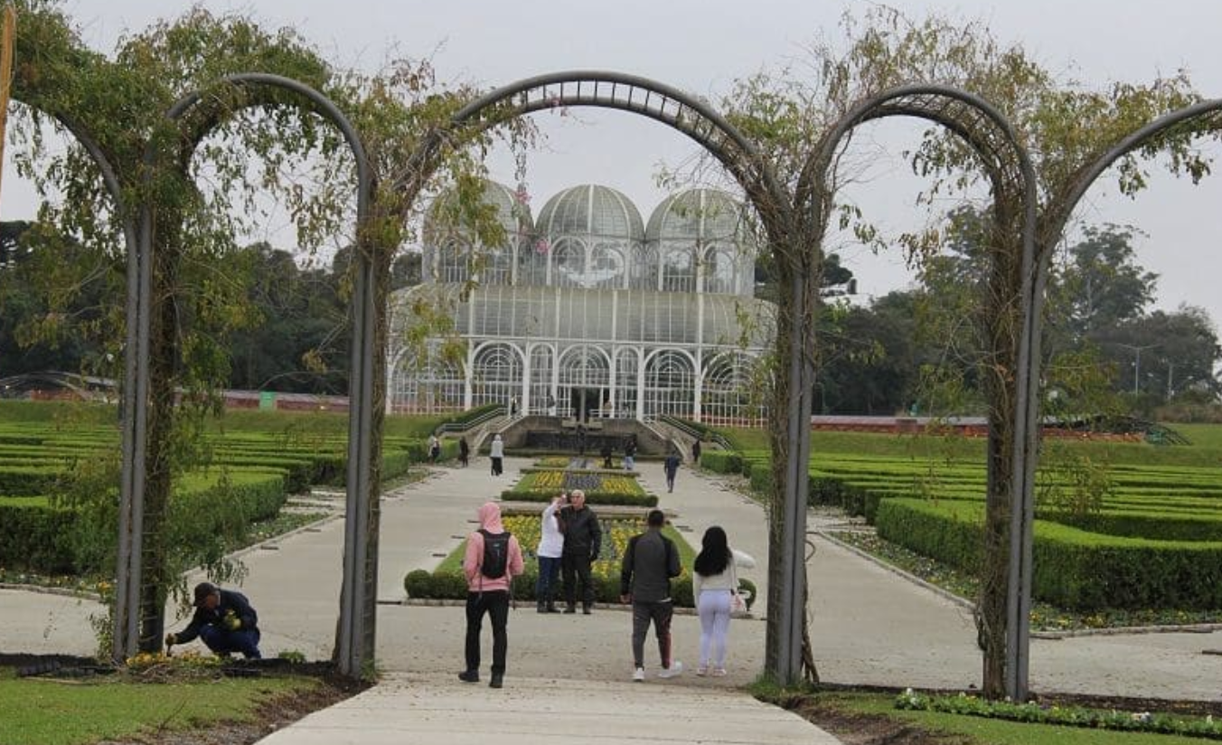 Família visitando o Jardim Botânico de Curitiba no inverno, estufa de vidro ao fundo