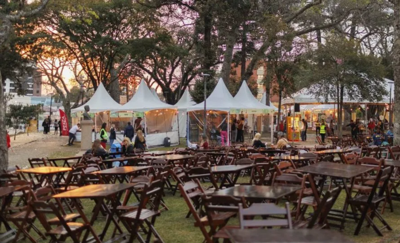 Festival gastronômico em Curitiba com barracas de comida típica paranaense e público animado
