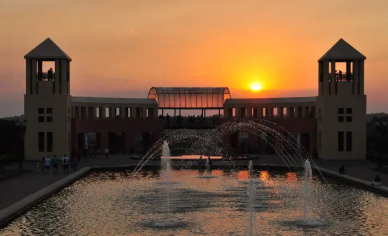 Parque Tanguá em Curitiba ao entardecer com lago artificial, ponte e vegetação dourada do outono