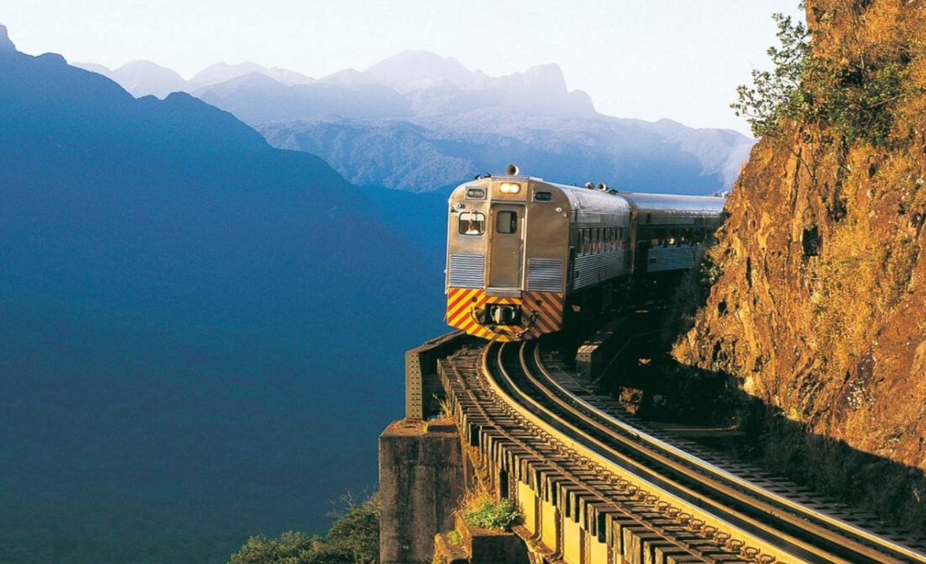Trem da Serra Verde Express cortando a Serra do Mar paranaense no inverno com névoa