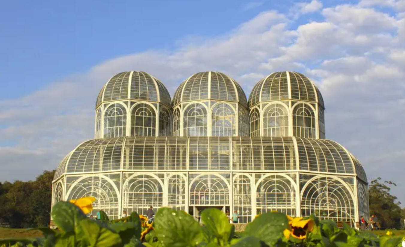 Estufa de ferro e vidro do Jardim Botânico de Curitiba cercada por jardins em estilo francês