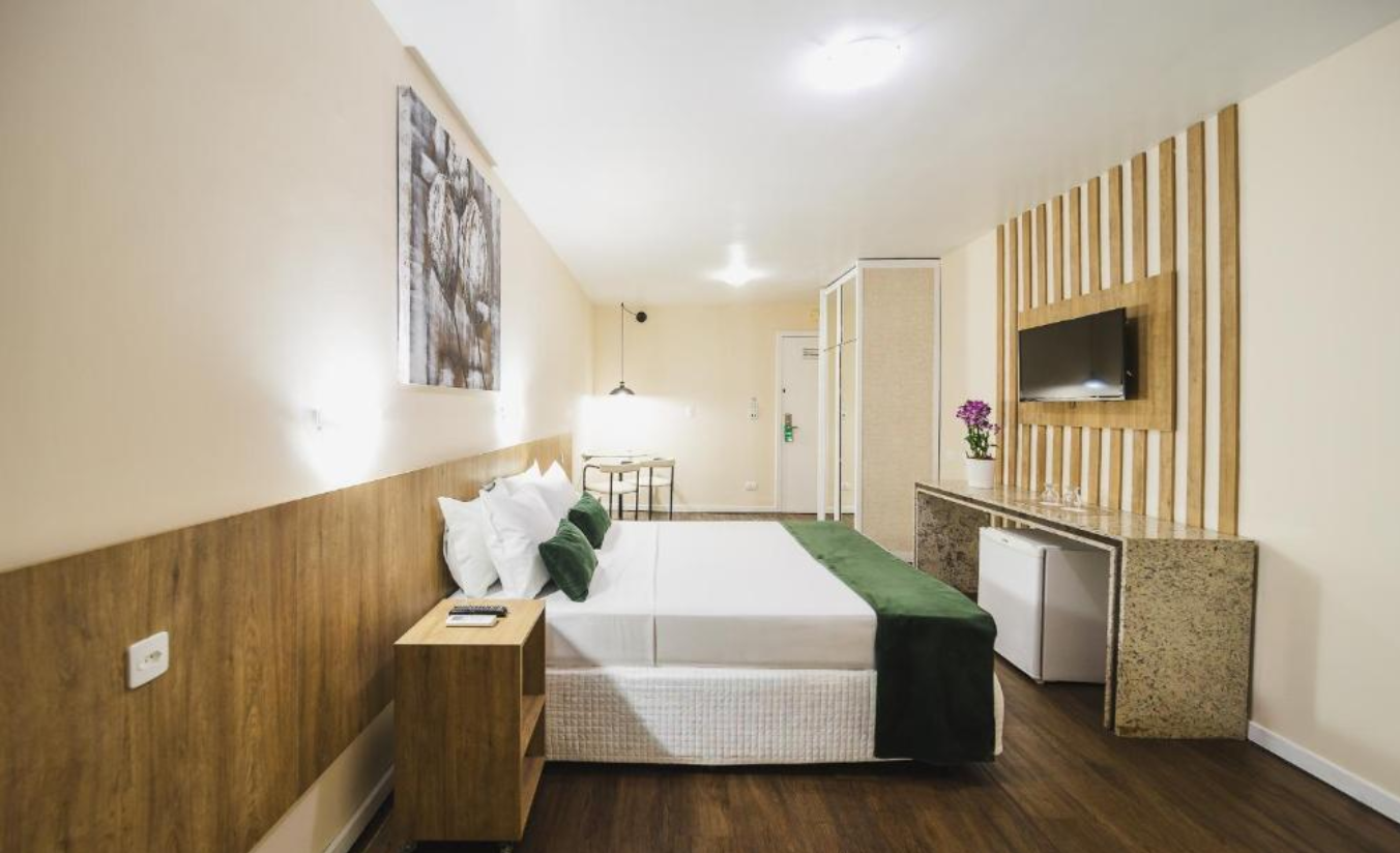 Quarto de hotel confortável e bem iluminado, ideal para viajantes a lazer ou a negócios em Curitiba